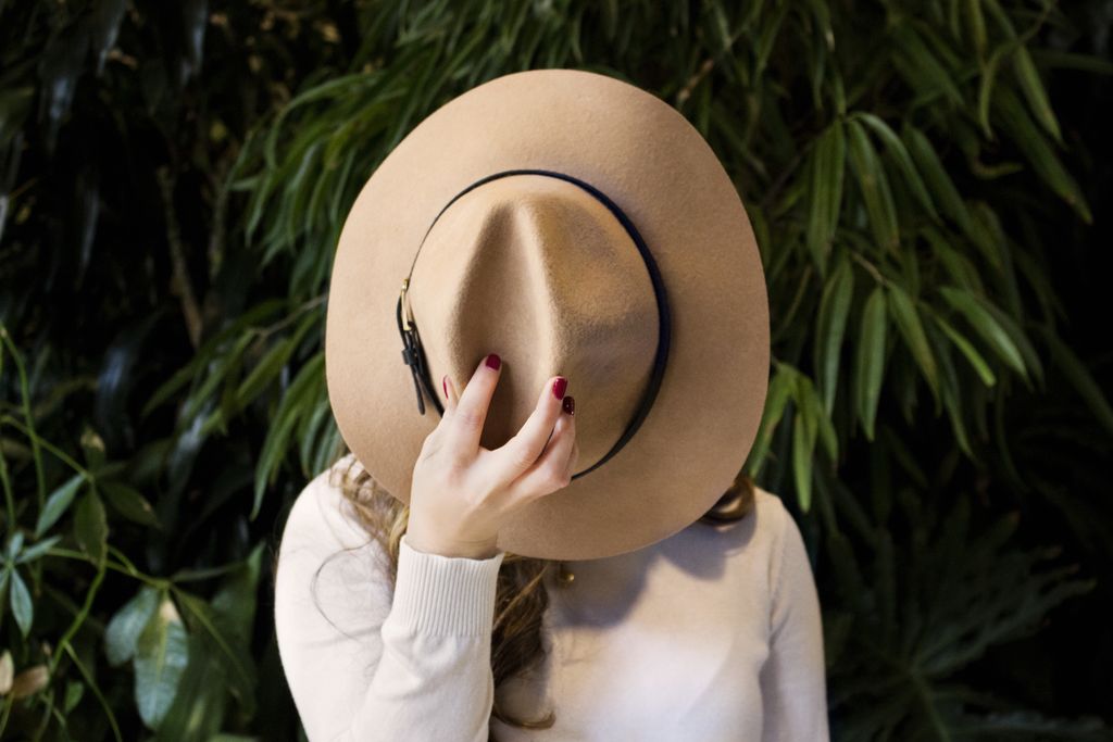 Girls holding a hat in front of her face