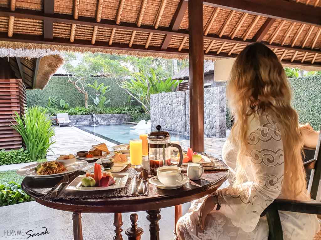 Fernwehsarah at the breakfast table at Kayumanis Ubud looking to their private pool in their Bali luxury villa